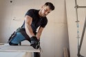 Fachowiec przycina płytę gipsowo-kartonową podczas remontu mieszkania