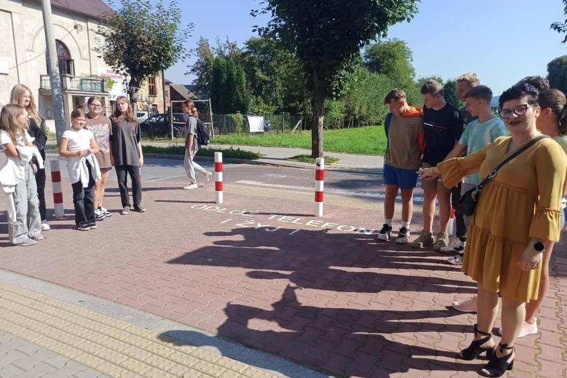 Nauczyciele i dzieci stojące przy przejsciu dla pieszych