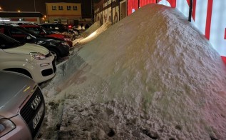 Góry śniegu z odśnieżania parkingu przy sklepie w Wadowicach